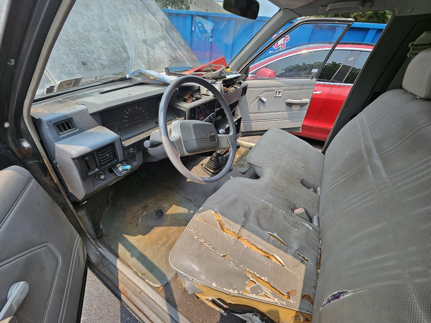 Filthy D50 cab with torn seat, dirty dash, debris, and cracked windshield area