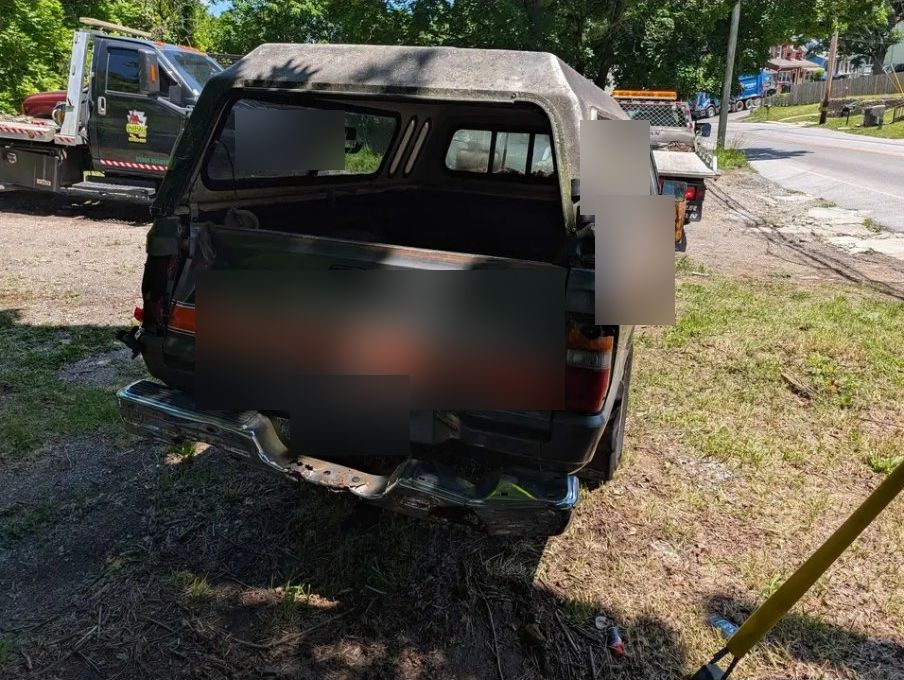 Rear of the Dodge D50 showing bed cap and bumper damage